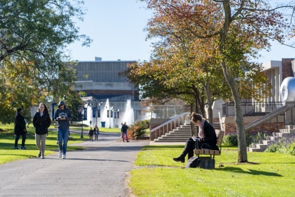Students on a path surrounded by grass and trees on the Ithaca College campus.